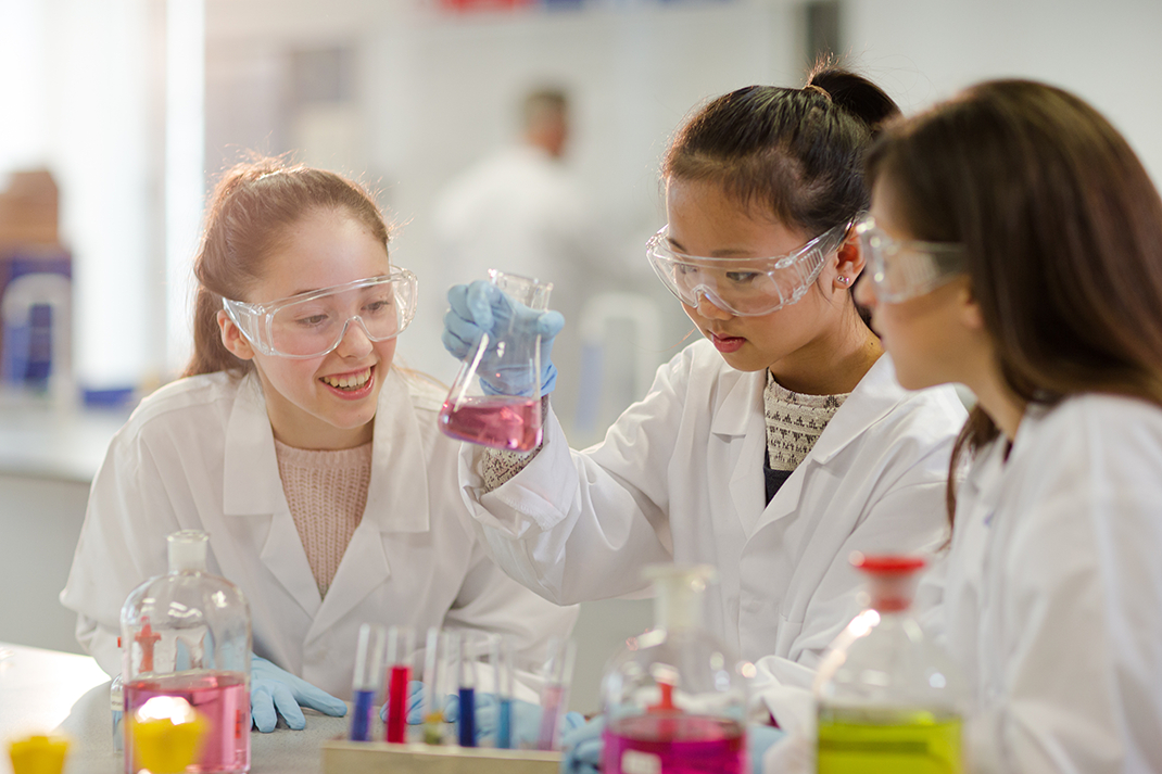 three students learning about science in the classroom