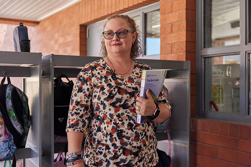 An educator stands out front of her classroom.