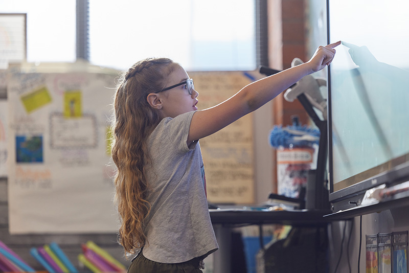 A young student works on a smartboard during a classroom activity.