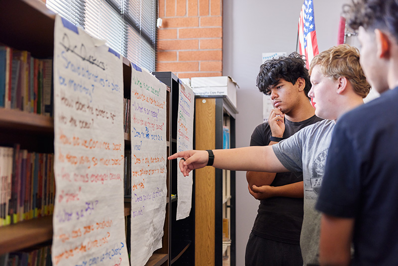 A group of students collaborate in front of handwritten posters.