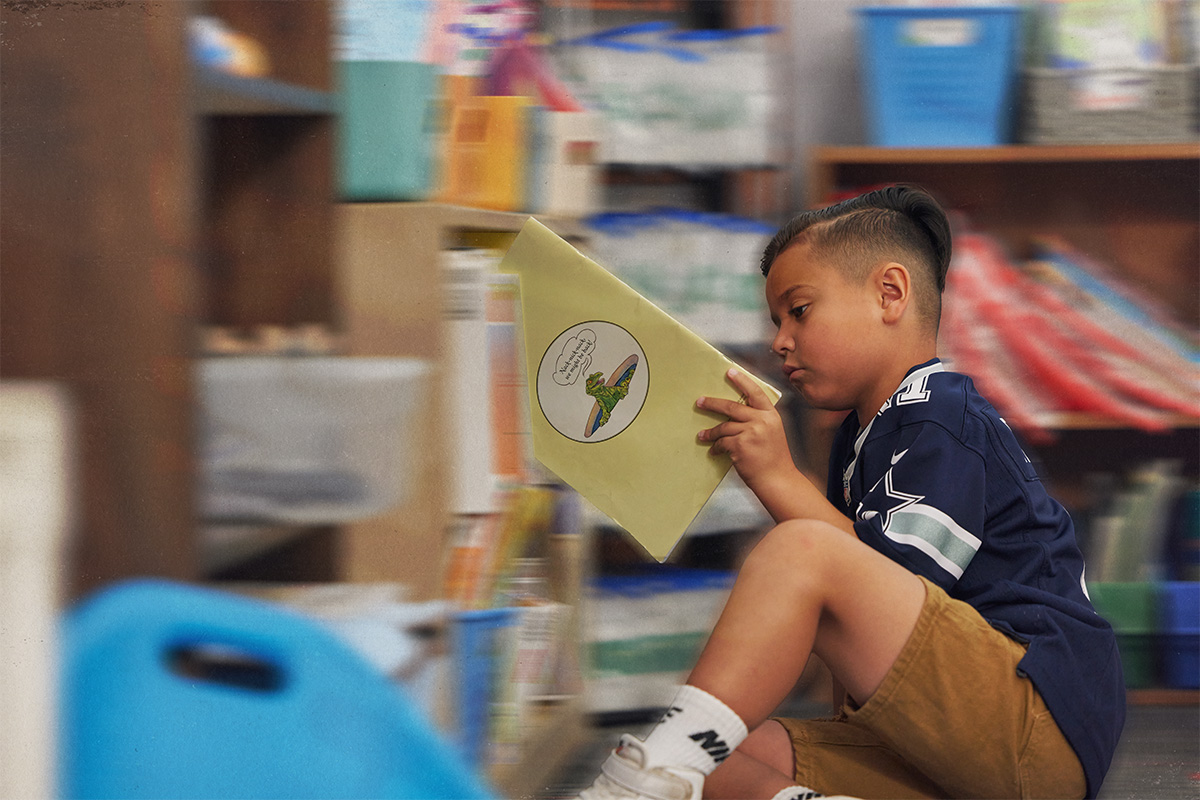 Boy looking at books in a book shelf.