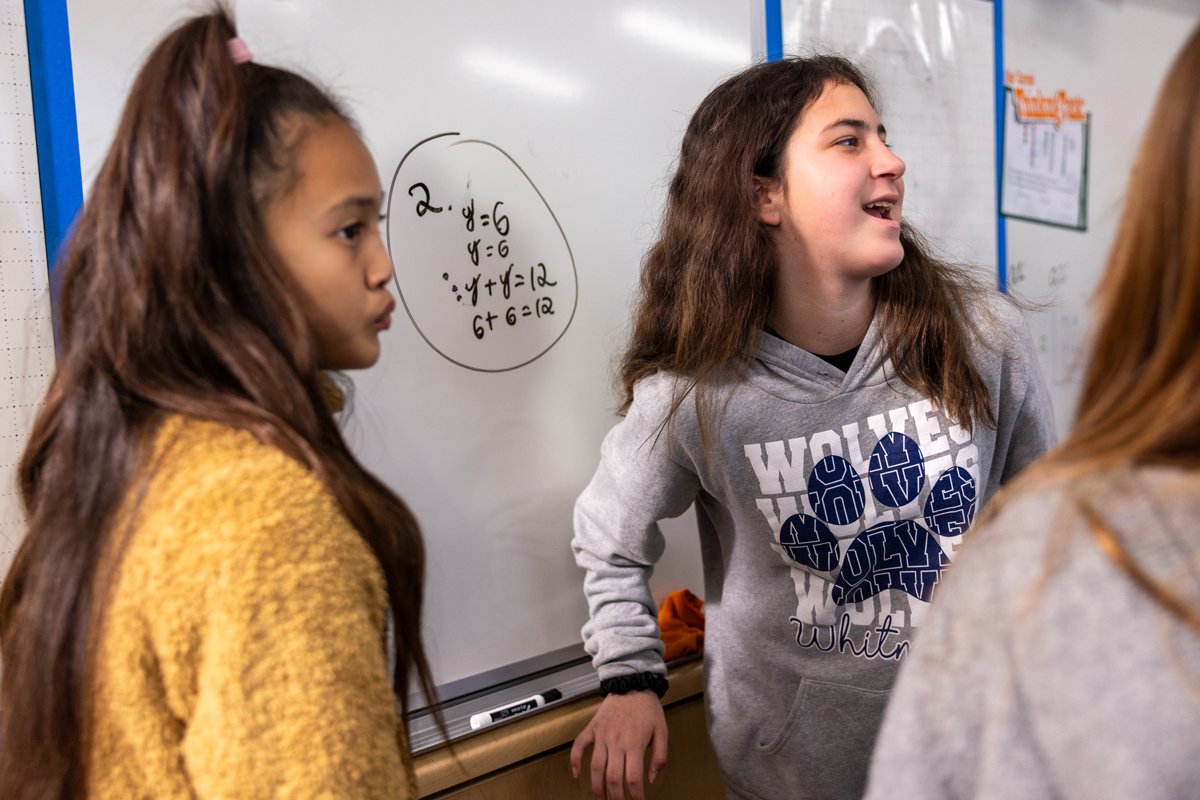 A group of female students solving a math equation on white board
